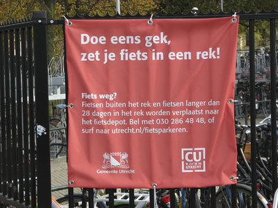 908048 Afbeelding van het gemeentelijke spandoek 'Doe eens gek, zet je fiets in een rek!', op het hek rond de ...